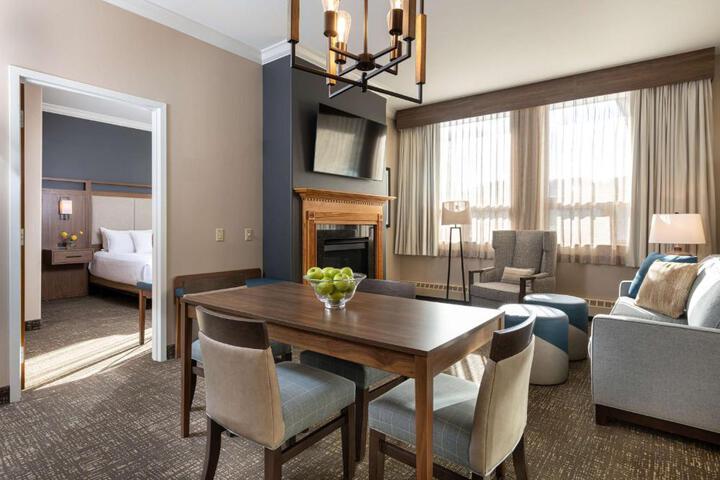 This King Bedded Room Is An Oversized Room This Room Comes with A Beautyrest Pillow Top Mattress Will Be Made Up with Premium Linens Duvet Blanket Plenty Of Pillows and Of Course Soft Plush Towels The Sitting Area Has 2 Club Chairs Facing A TV with Direct TV Service A High Top Table with Chairs Offers A Place To Eat Work or Play Games Plenty Of Charging Ports Free High Speed WiFi Iron and Ironing Board (1 of 21)